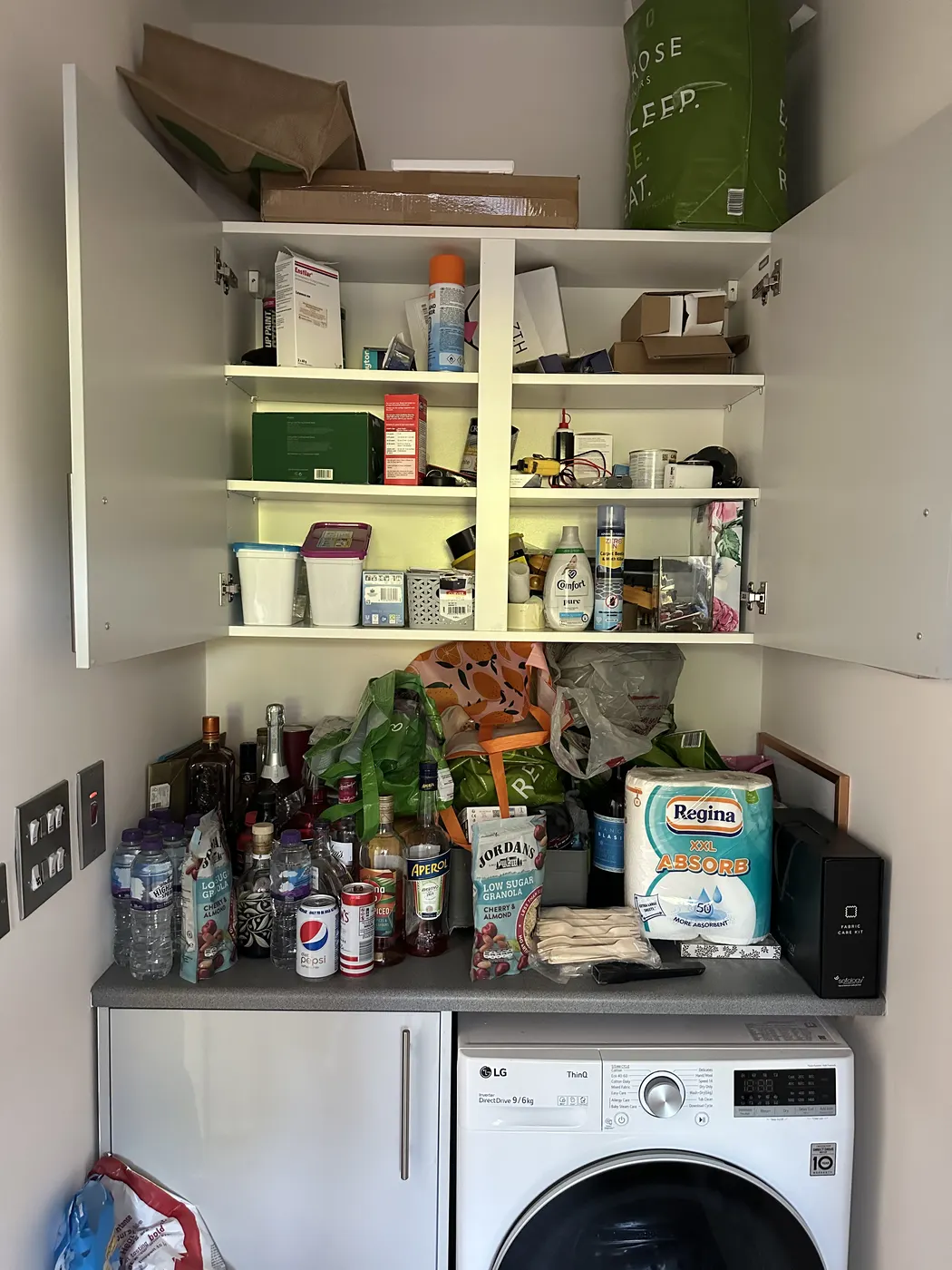 Utility cupboard before: shelves overflowing with bottles and cleaning products