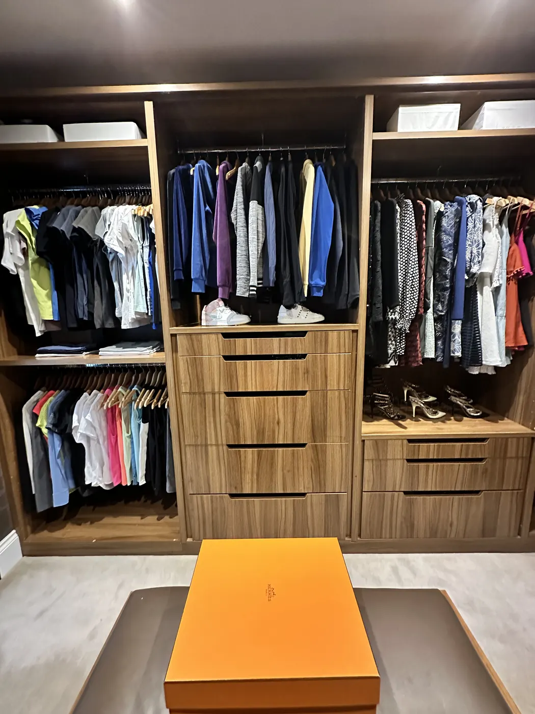 Dressing room after: walnut shelves, shoes in rows and an ottoman in the middle