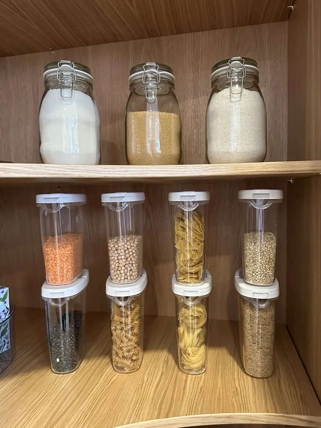 Pantry canisters of pasta, pulses and flour lined up on a shelf