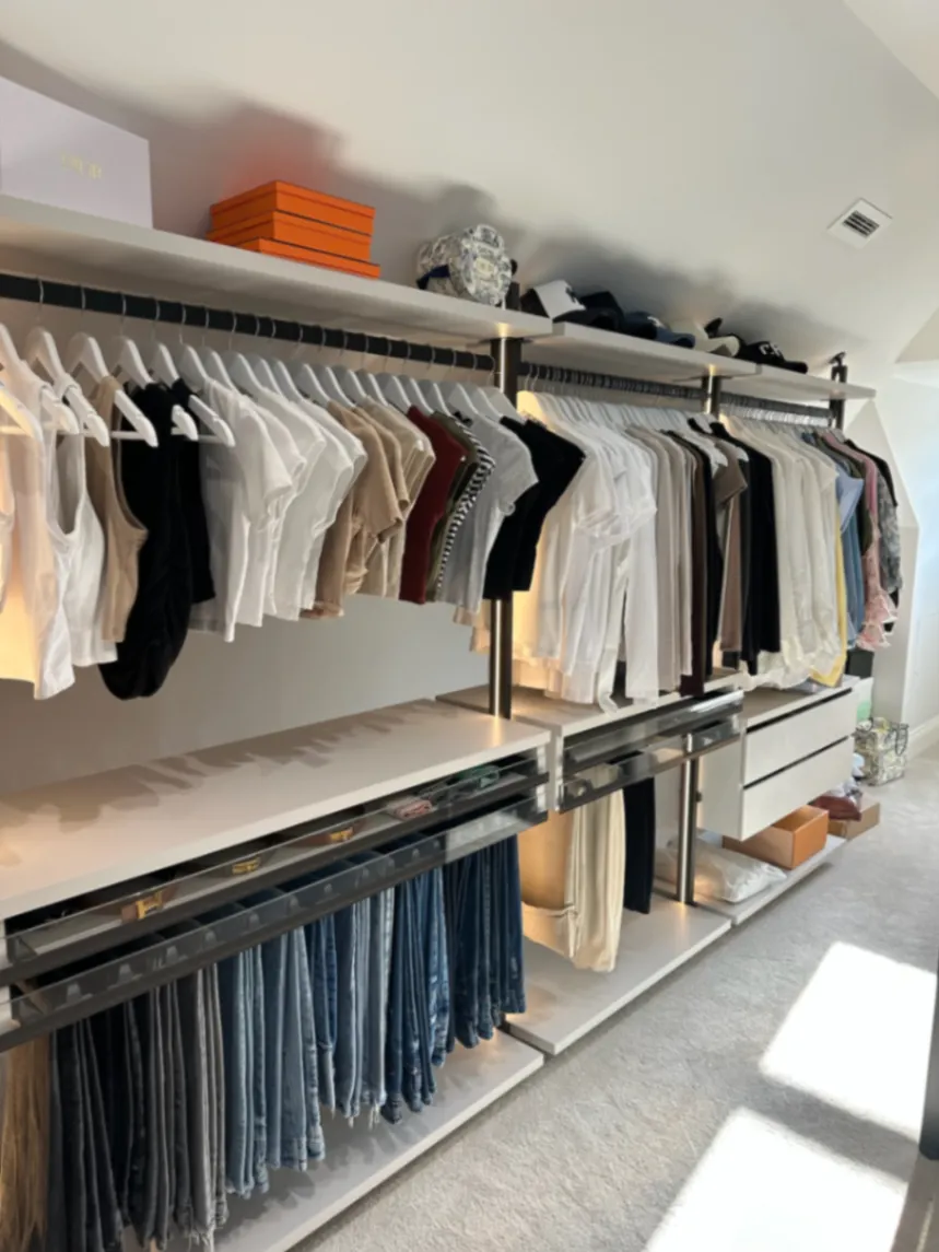 Light wardrobe with clothing on matching hangers and drawers below