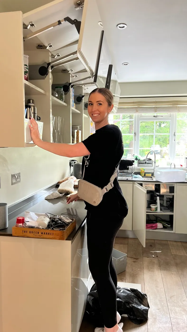 Ruth arranging belongings in a kitchen cupboard