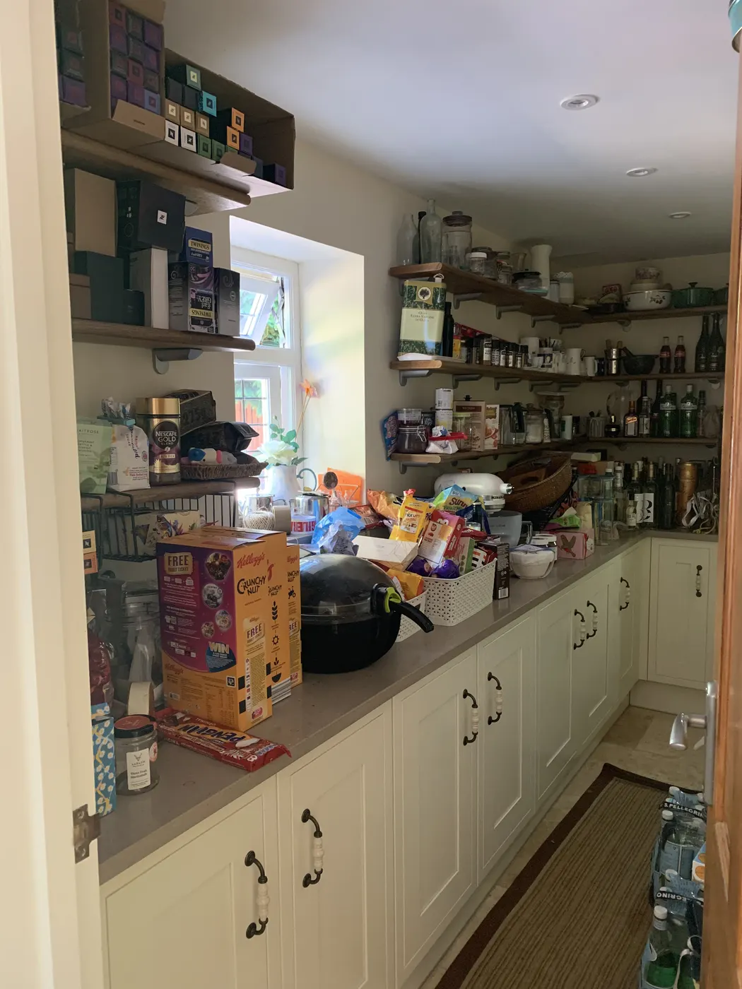 Kitchen worktop and open shelves crowded with food and cookware before organising