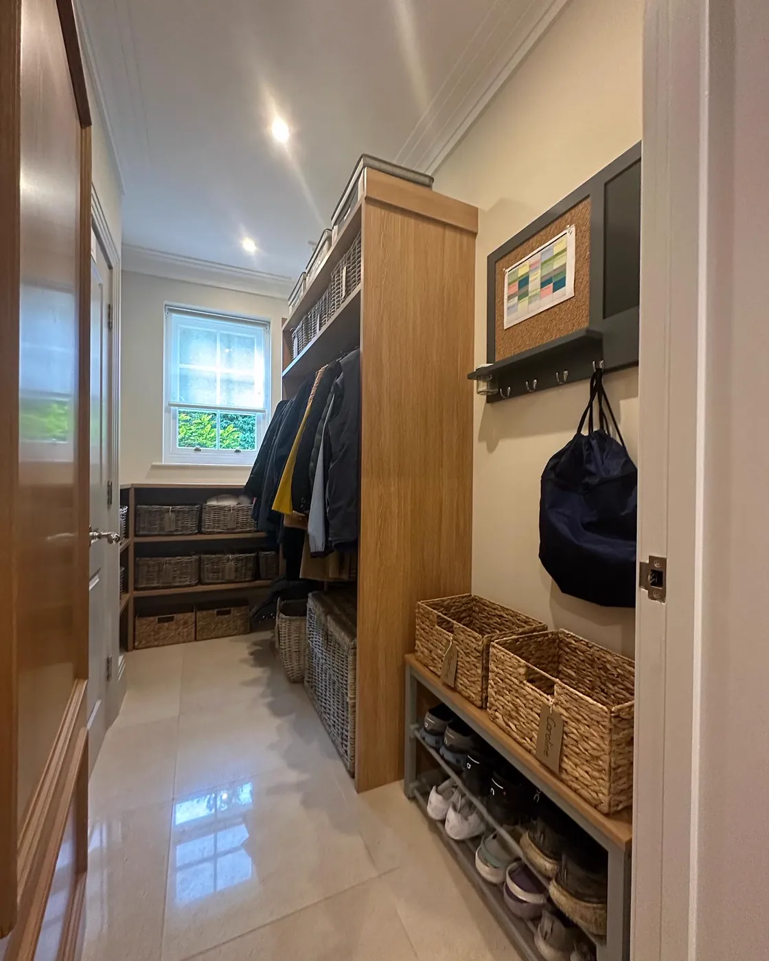 Boot room after: baskets labelled and coats hung, with a family calendar on the wall