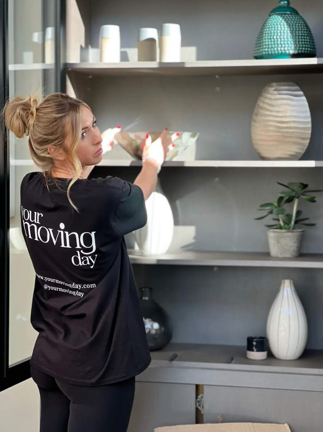 Ruth wearing her Your Moving Day shirt while arranging unpacked belongings