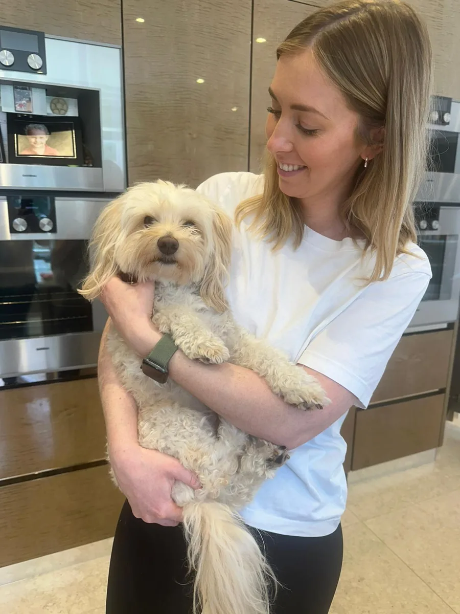 Ruth holding a small dog in a kitchen