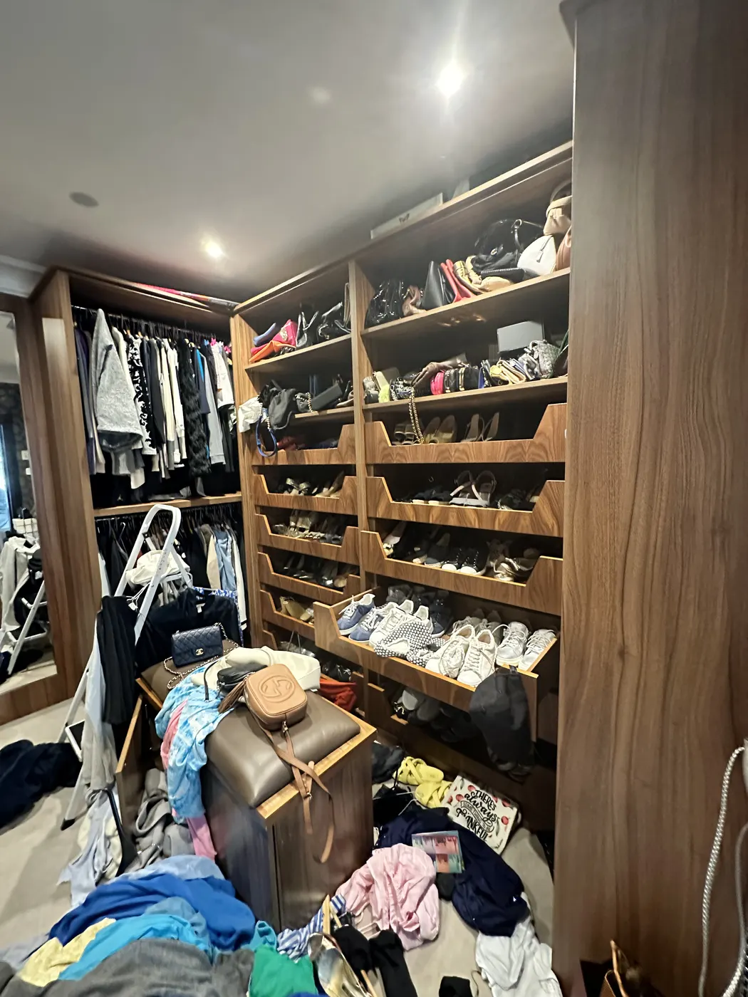 Dressing room shoe shelves before, with clothes heaped in front