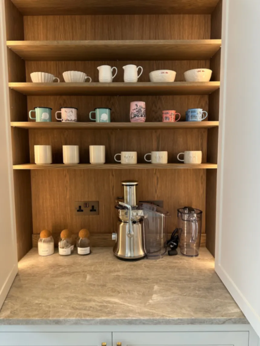 Mugs and glasses arranged on kitchen cupboard shelves