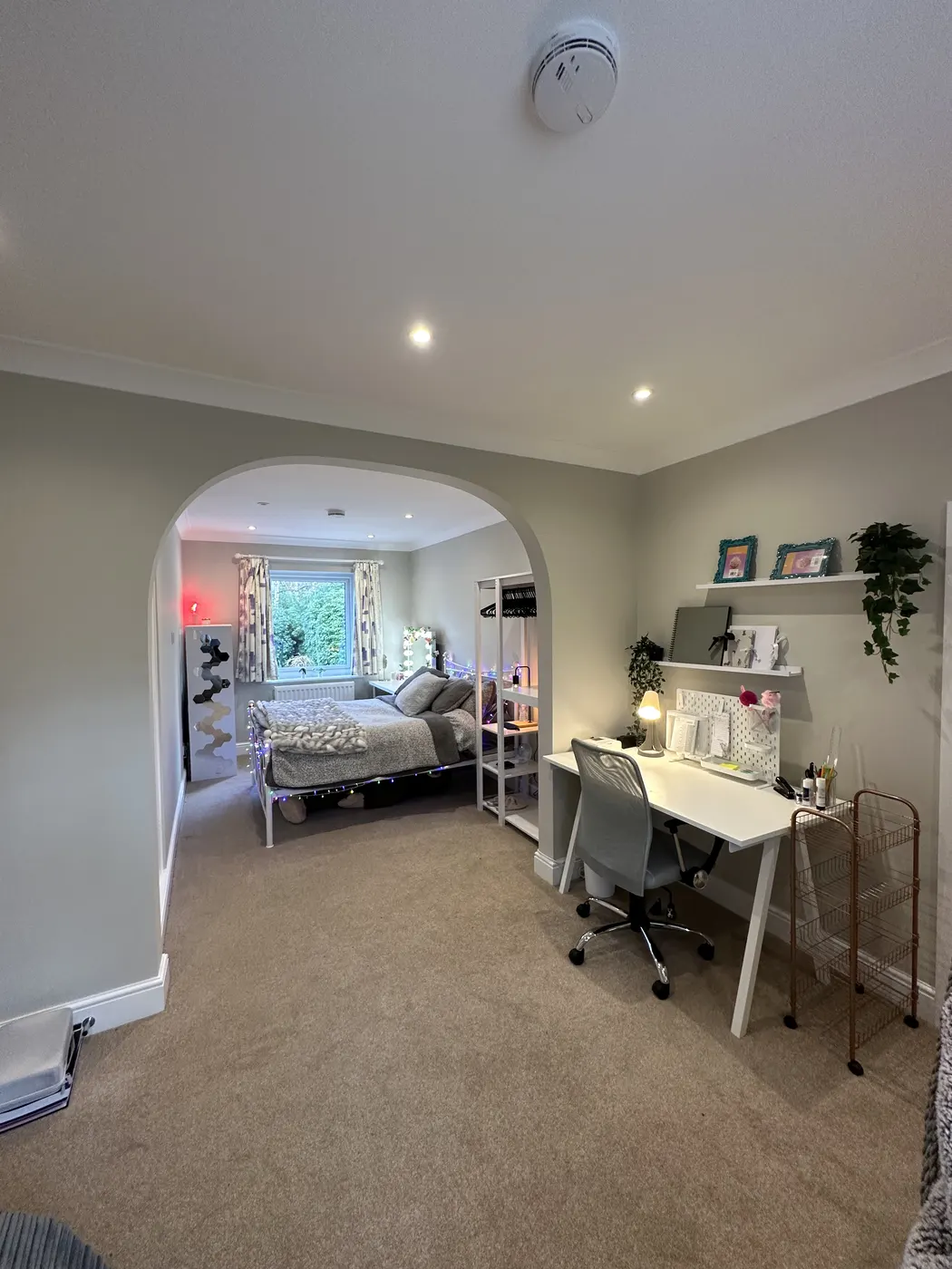 Bright, tidy bedroom seen through an arch with a clear desk