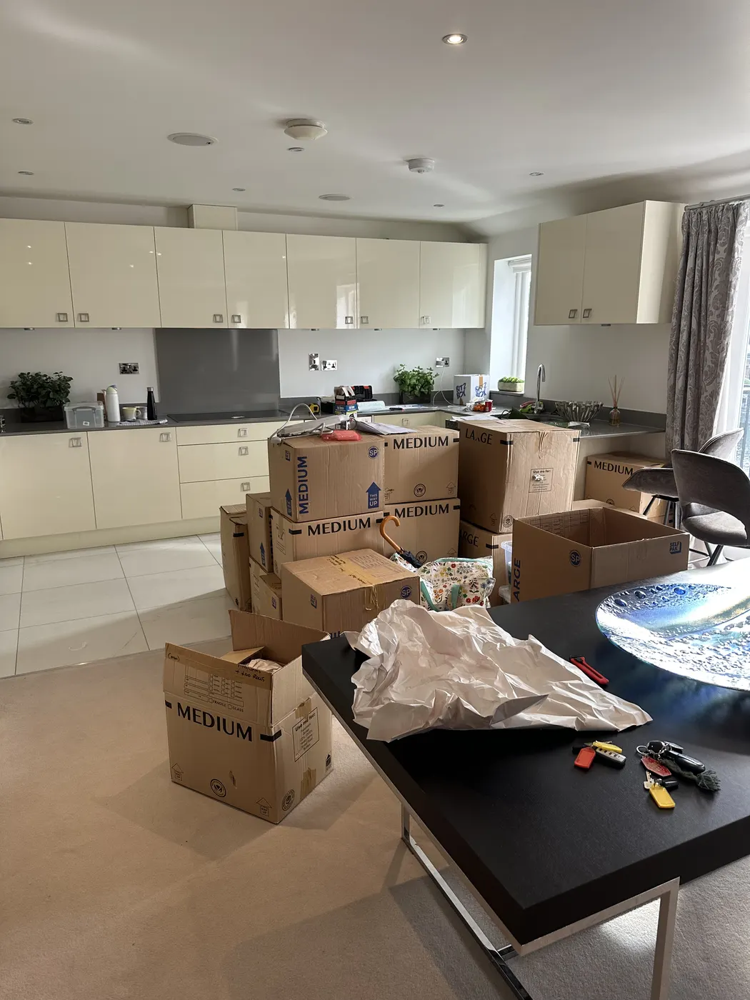 Kitchen on moving day, island covered in unopened boxes