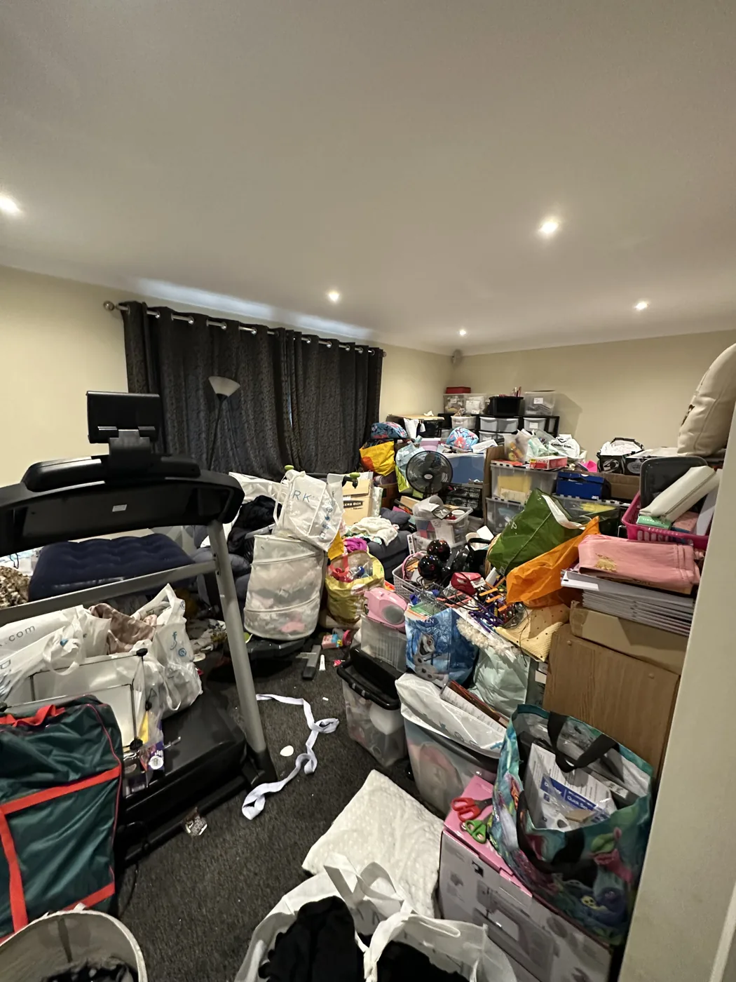 Living room before decluttering, with belongings piled across the floor and sofas