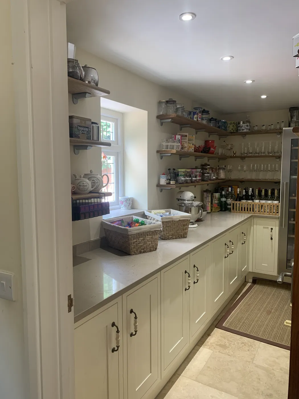 Same kitchen shelves after: food grouped in baskets and the worktop clear